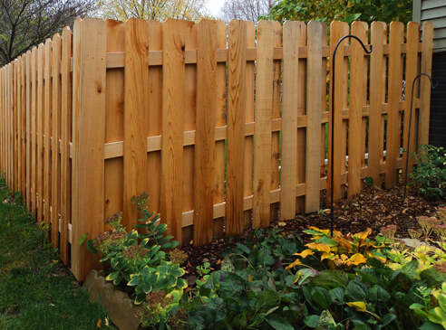 Long, natural colored fence around house.